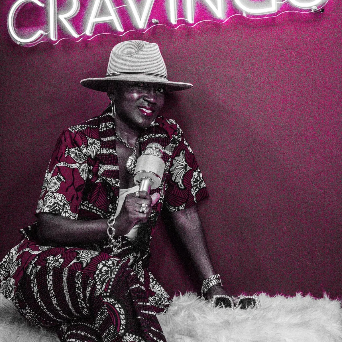 Charise on stage with vintage mic under neon Cravings sign